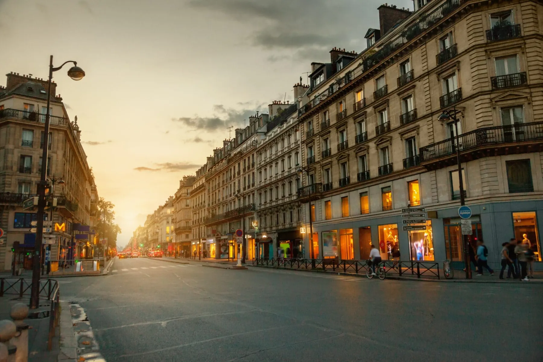 Rue commerçante parisienne au coucher du soleil, commerces et immeubles haussmanniens